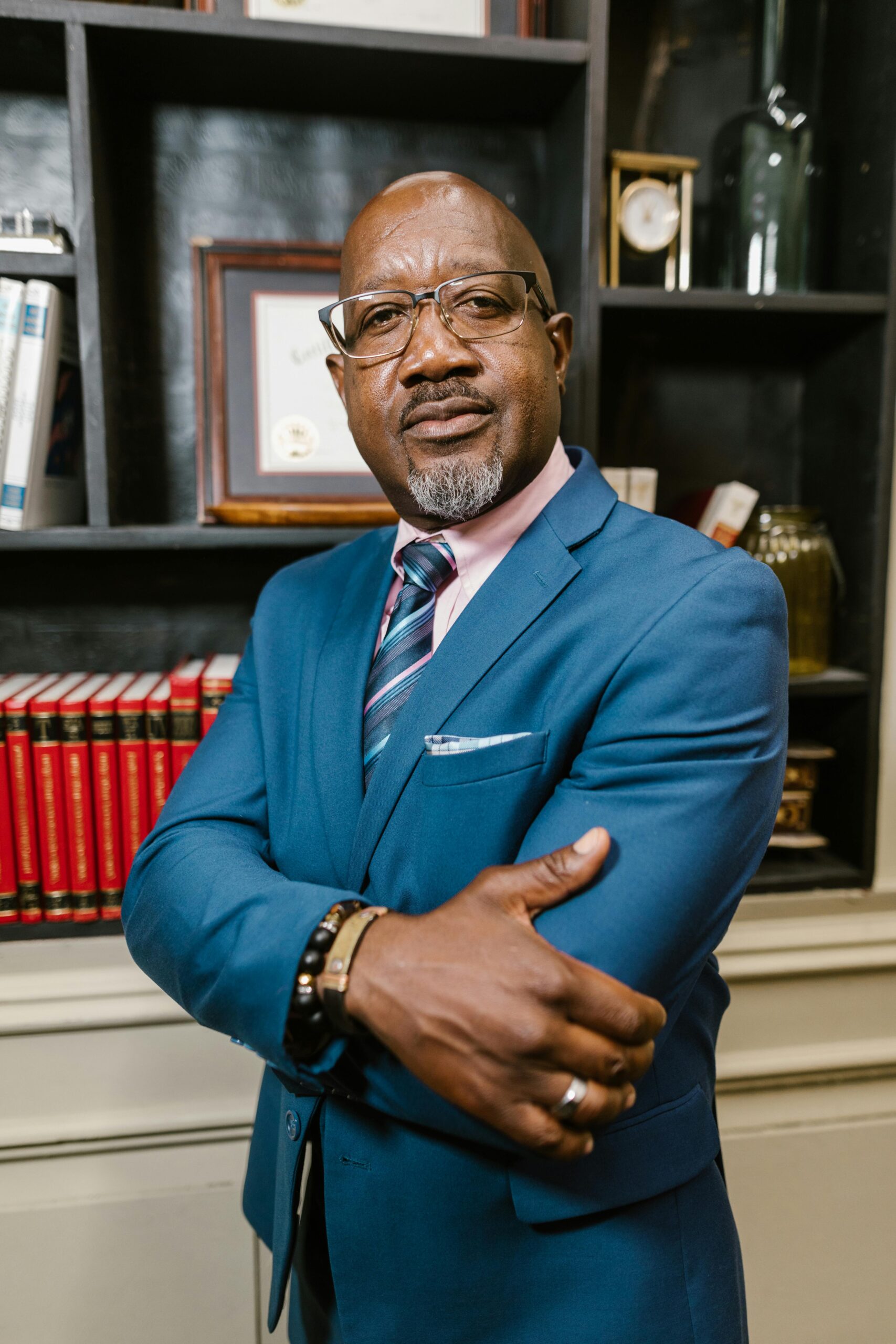 Mature businessman in business attire with arms crossed in a modern office setting.